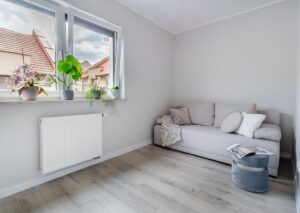 Przytulny pokój gościnny z sofą i szarym pufem szeregowiec Poznań okolice.