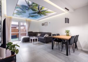 Salon z podświetlanym sufitem napinanym i widokiem na taras Czapury.